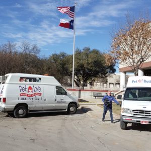 Two service vans and a worker outside under clear sky with flags.