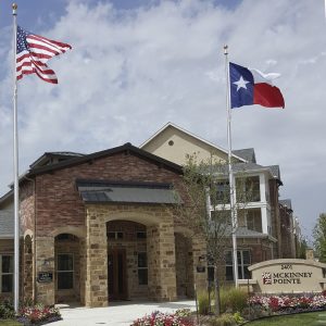 Entrance of a community center with American and Texas flags fluttering.
