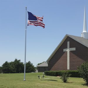 American flag flying beside a church building on a clear day.