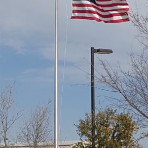 American flag flying on a flagpole under a clear blue sky.