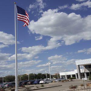 American flag waving on a tall pole against a blue sky with clouds.