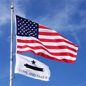 American flag and 'Come and Take It' flag flying against a blue sky.