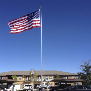 American flag waving on a tall pole against a clear blue sky.
