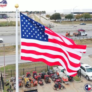 American flag waving near highway and vehicles.