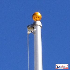 A flagpole topped with a pumpkin decoration against a clear blue sky.