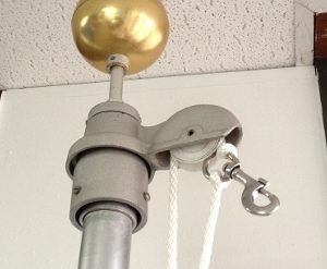 Close-up of a gray metal pulley system with a golden ball on top.