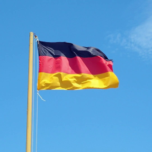 The German flag waving against a clear blue sky.