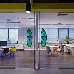 Modern office space with colorful surfboard decor and various seating options.